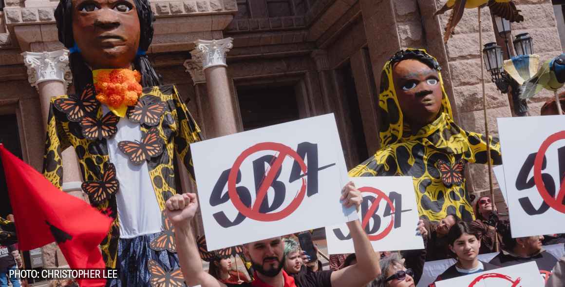 sb4 puppets in front of Texas capitol holding sign that reads no sb4