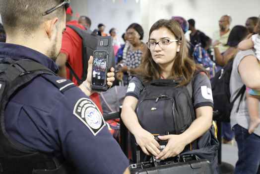 a young woman in line at the airport has her face scanned by a U.S. customs and border protection agent