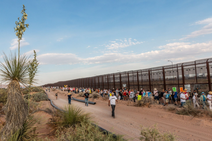 Photo: Immigrants' rights supporters lined up to march alongside a stretch of Border Wall in El Paso, Texas
