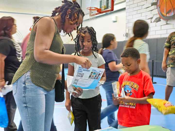 An adult and two children learn about the Students' Rights Hub