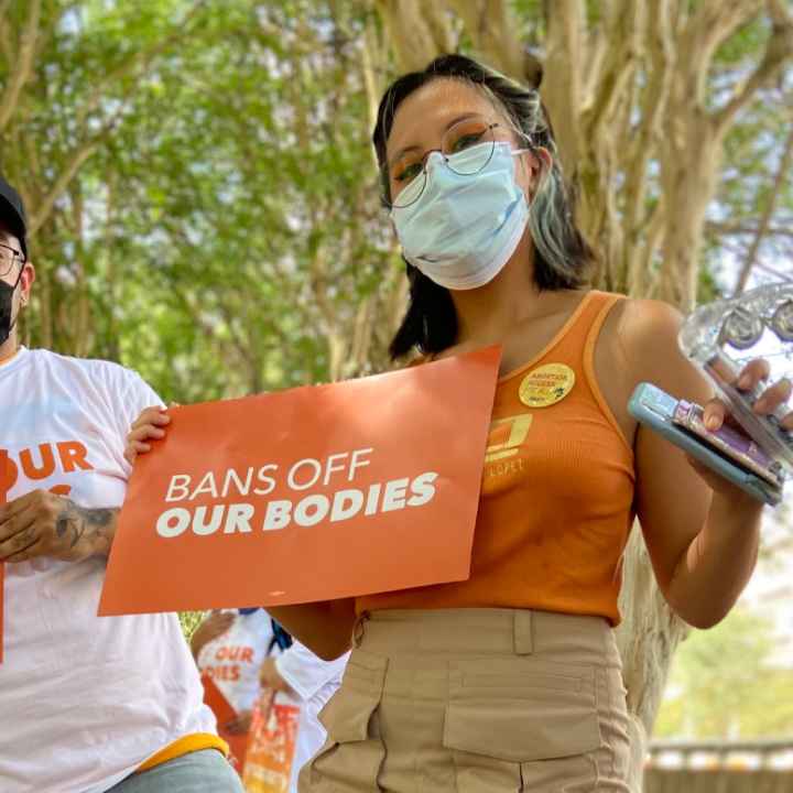 Two people holding signs that say Bans off our bodies